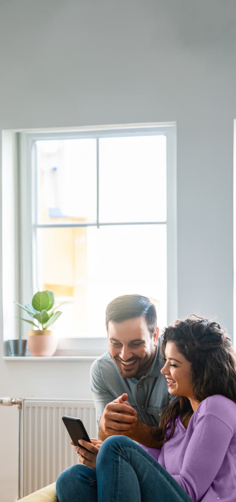 A picture of a couple smiling while looking down at the phone.